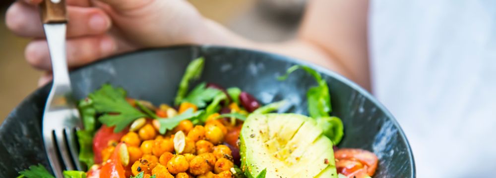 Woman eating healthy vegan meal from black bowl 