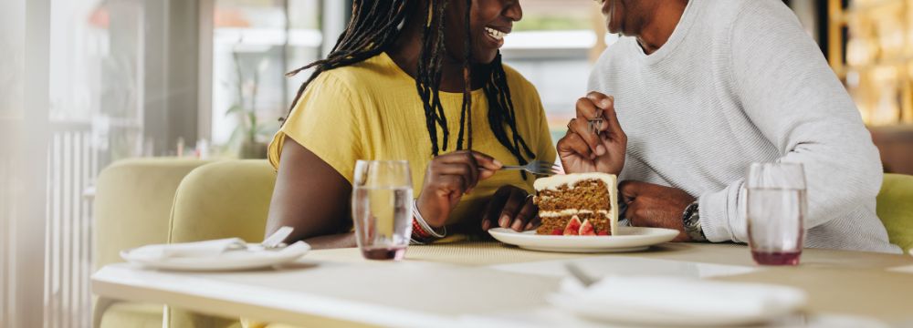 Man and woman sharing piece of cake at restaurant 