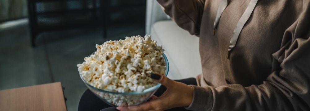 Woman eating popcorn out of glass bowl 